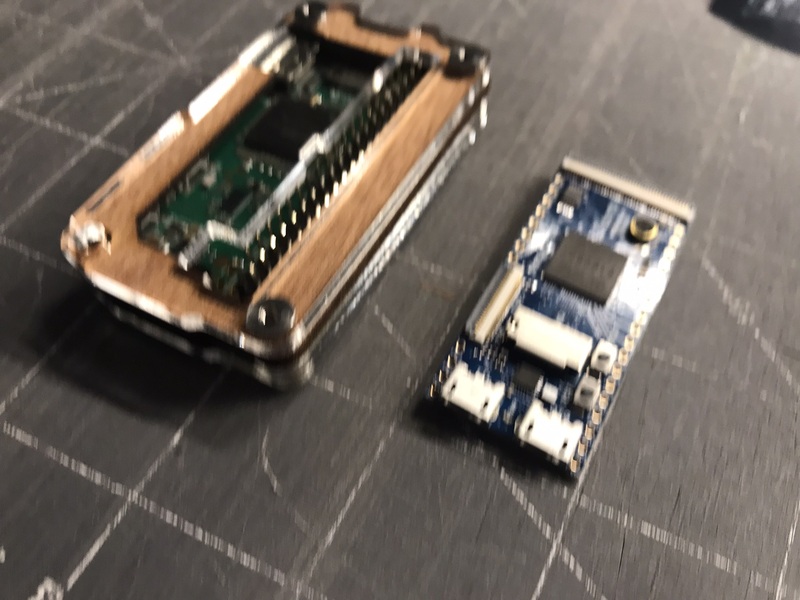 Two tiny single-board computers, one in a case and an even smaller one taking up just two one-inch squares on a scarred cutting board.