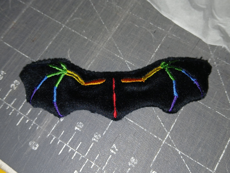 A terrible picture of a spectrum dragon wing on a scarred cutting mat.