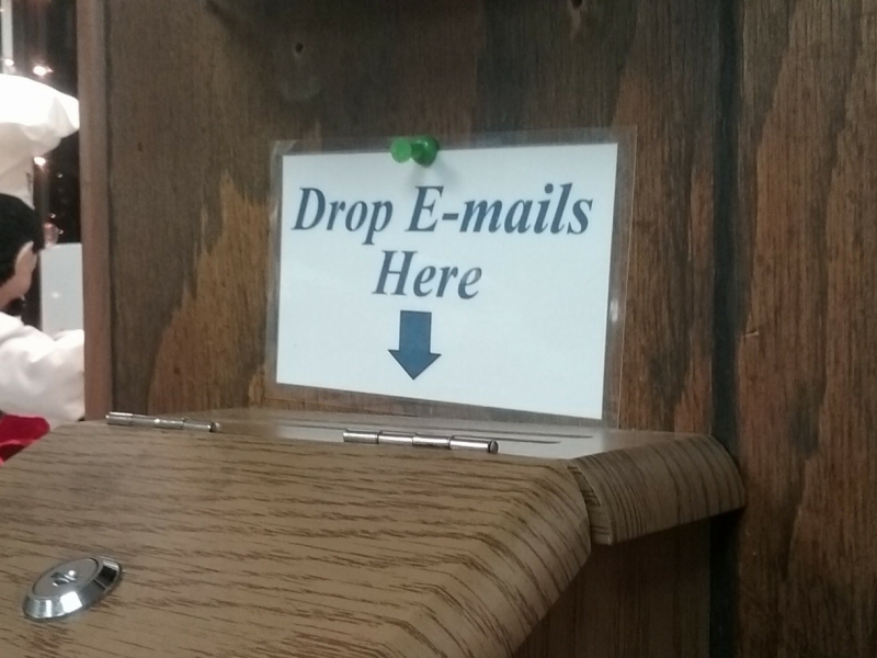 A wooden suggestion box, with a sign that reads Drop Emails Here.