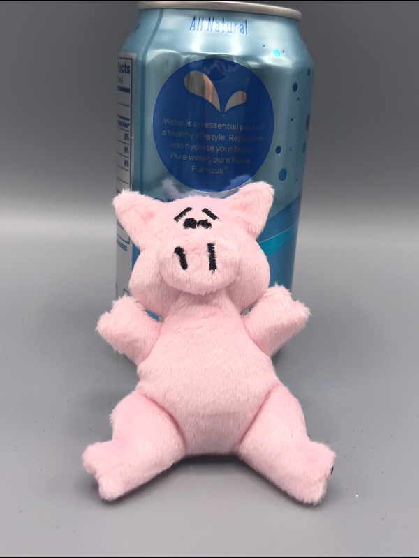 A cartoony plush pig, half the size of the seltzer can.