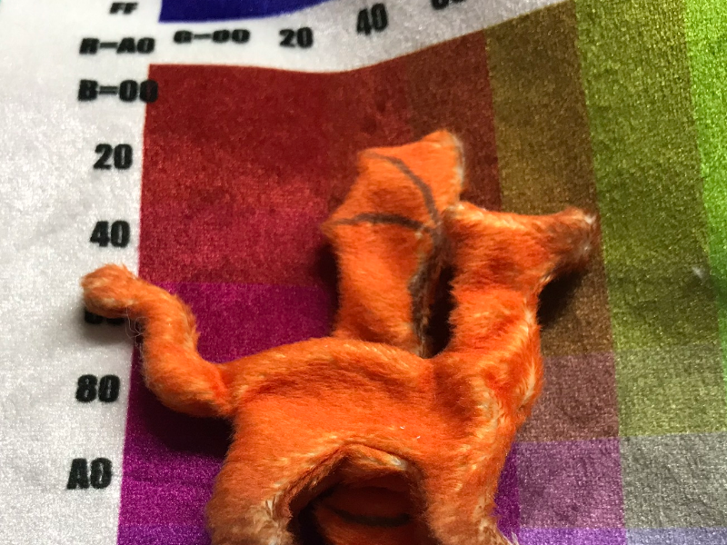 The same foxy dragon, on top of a chart of colors printed on upholstery velvet.