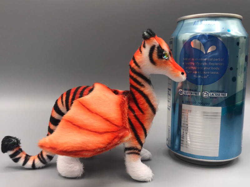 A tiny plush dragon, shorter than a can of seltzer