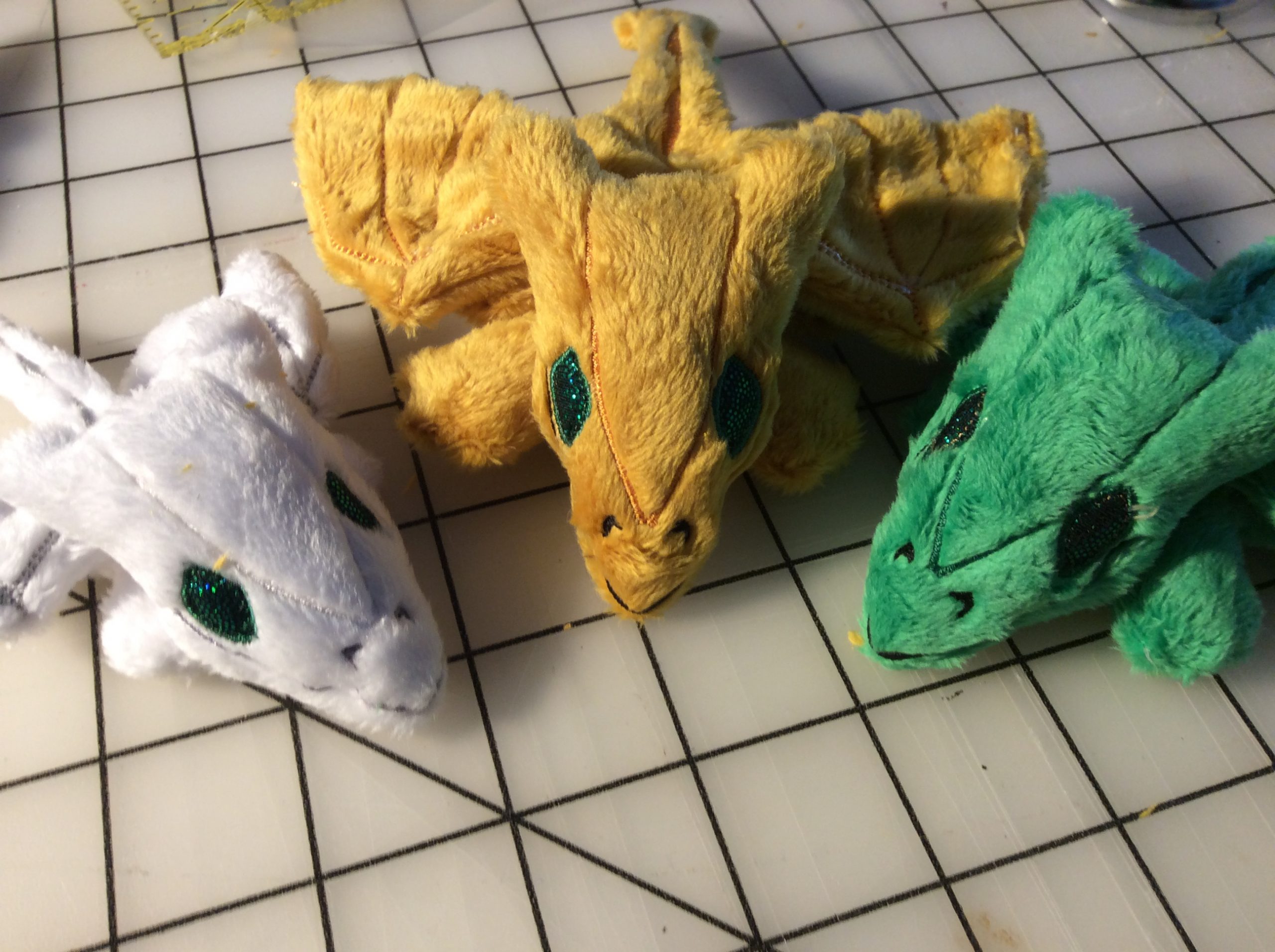 White, gold, and green tiny plush dragons.