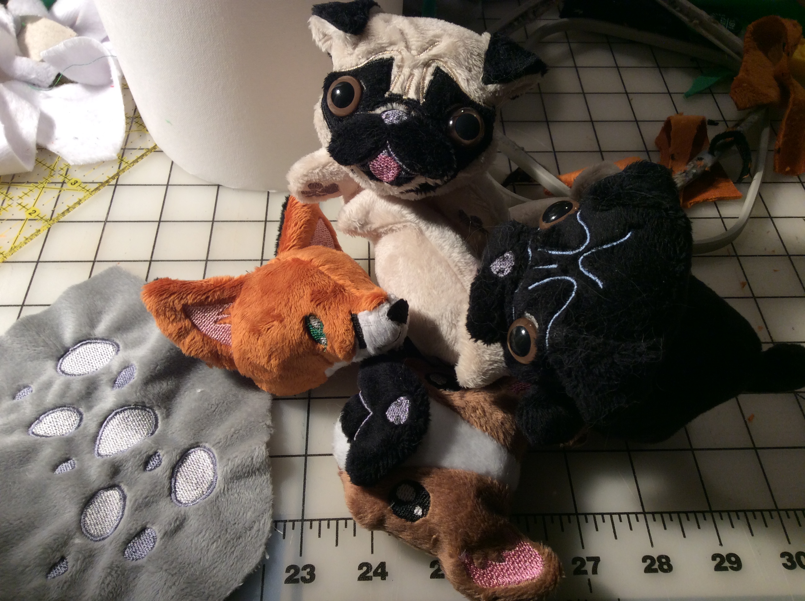 Three pugs, a fox head, a frenchie head, and a piece of fabric with some embroidered spots.