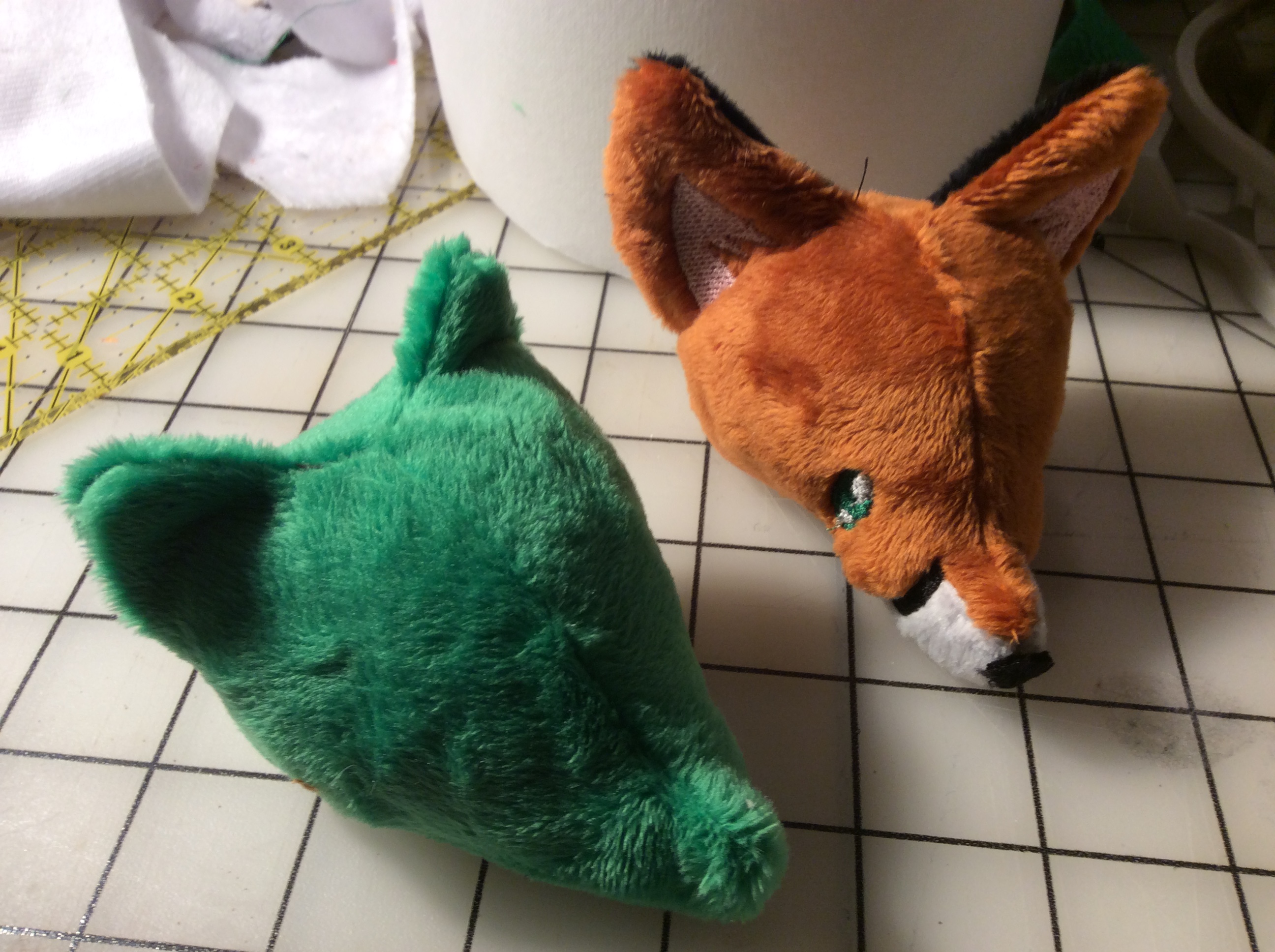 A blank green not-a-raccoon head next to a more finished fox head.