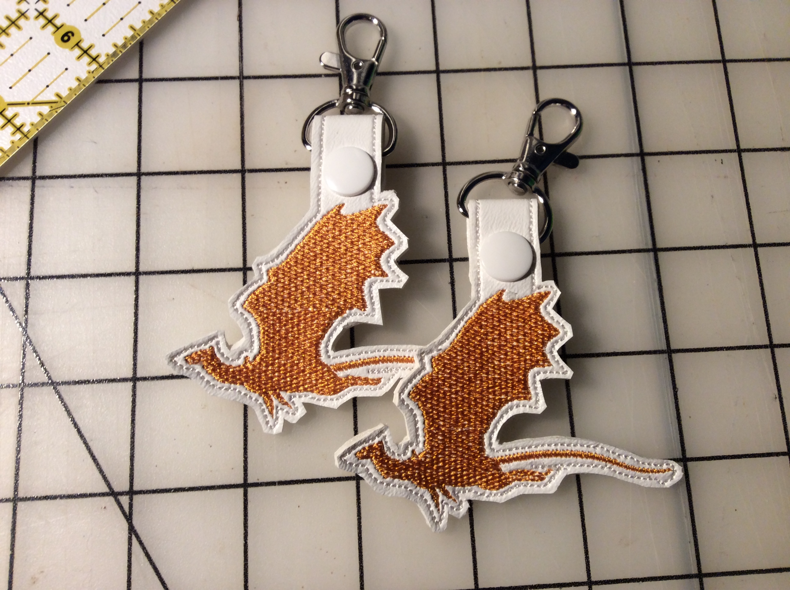 A pair of dragon silhouettes embroidered as snap tabs.
